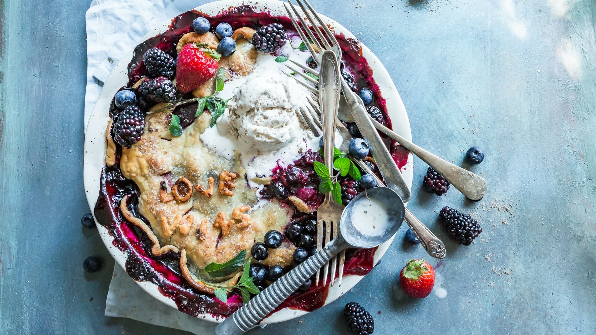 A beautiful arrangement of Mediterranean diet desserts, including a bowl of Greek yogurt with berries and figs, an olive oil cake, and grilled peaches.