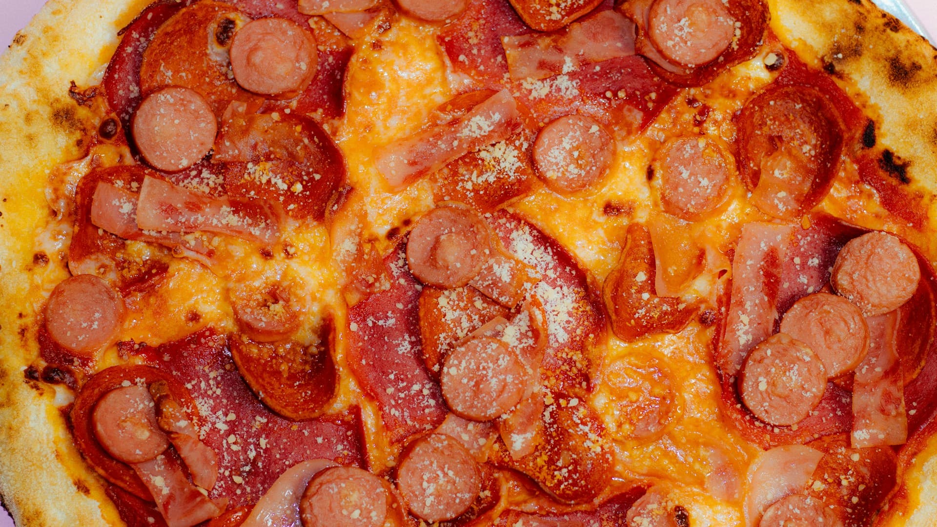 A close-up of a carnivore pizza topped with pepperoni, bacon, and melted mozzarella cheese.