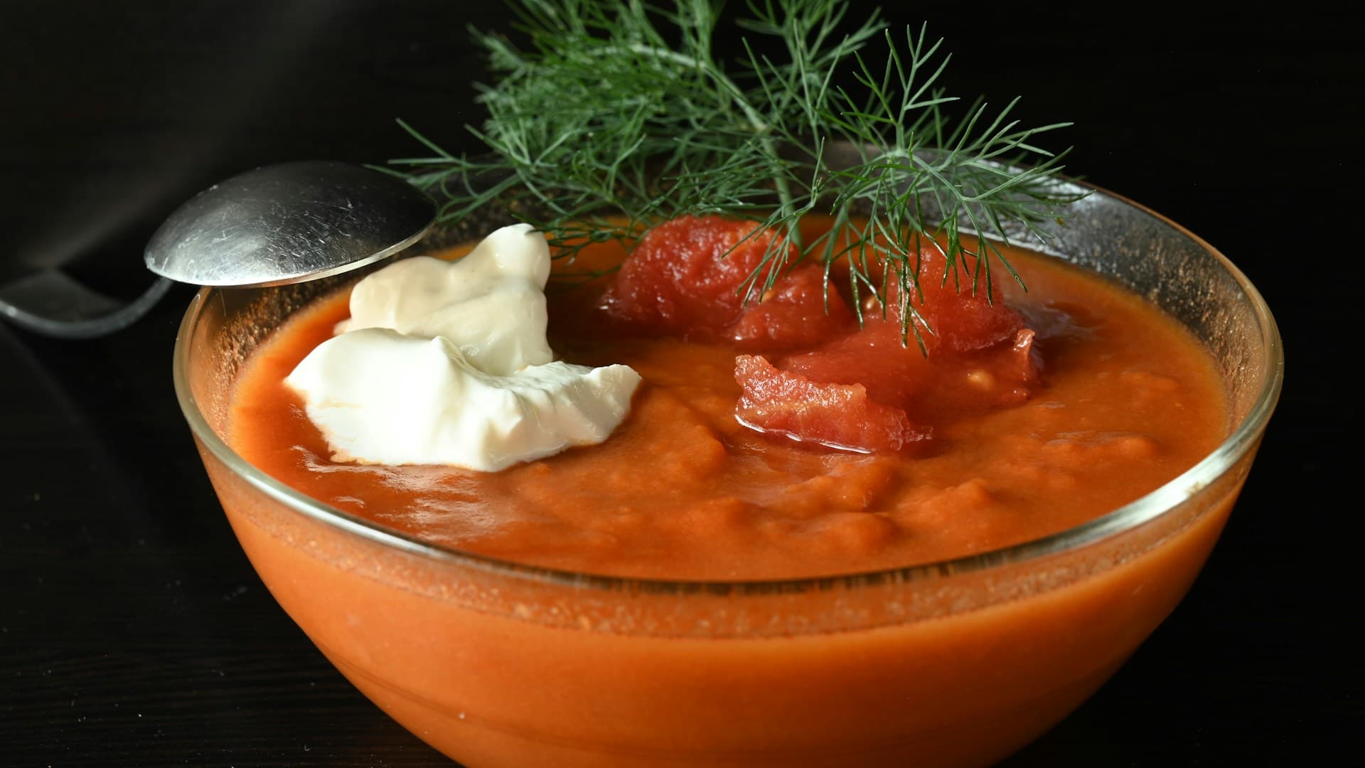 A close-up of a creamy roasted tomato and basil soup in a white bowl.
