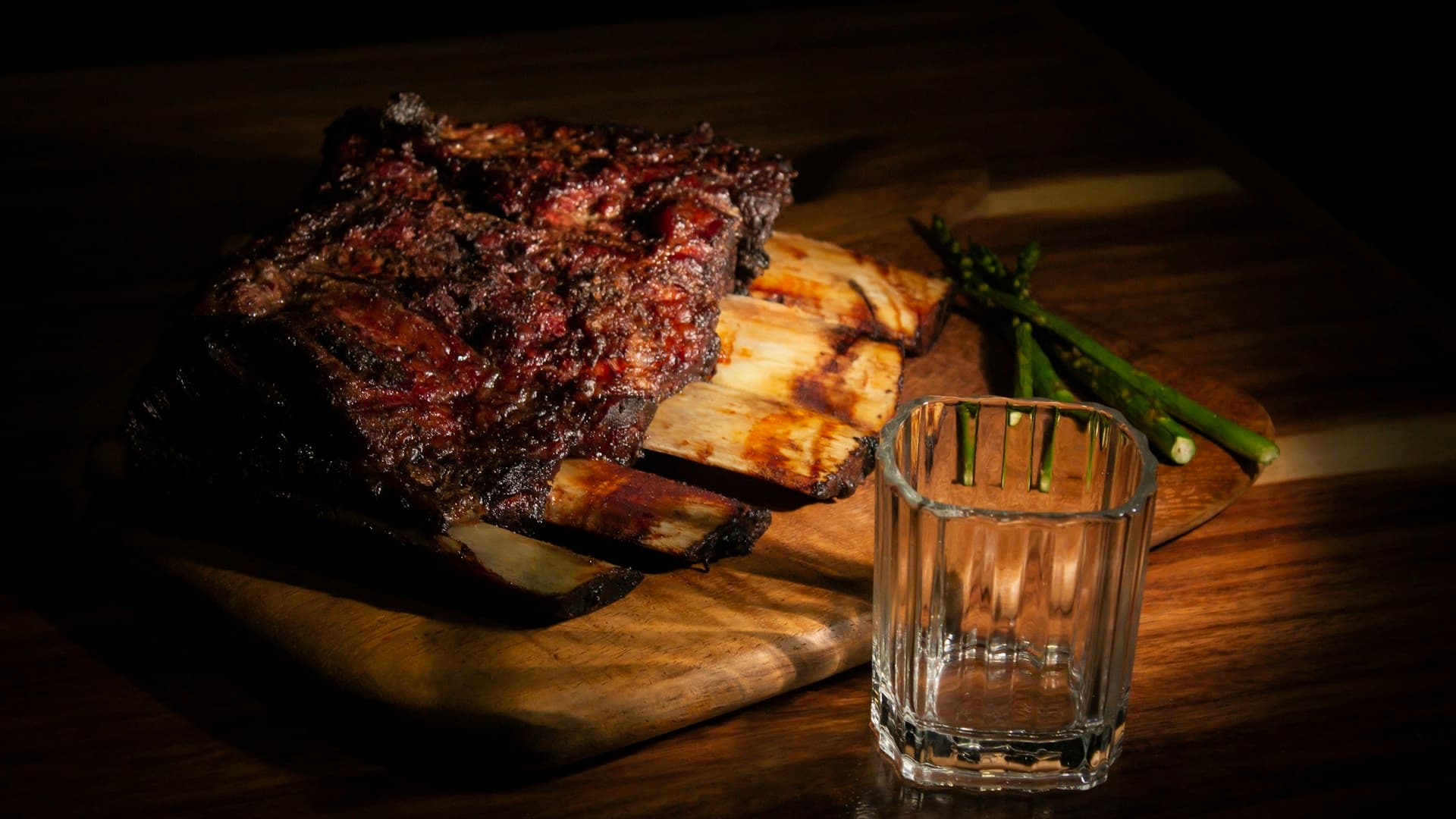 A close-up of a glass of whiskey on a rustic wooden table next to a perfectly cooked steak, illustrating alcohol on the carnivore diet.