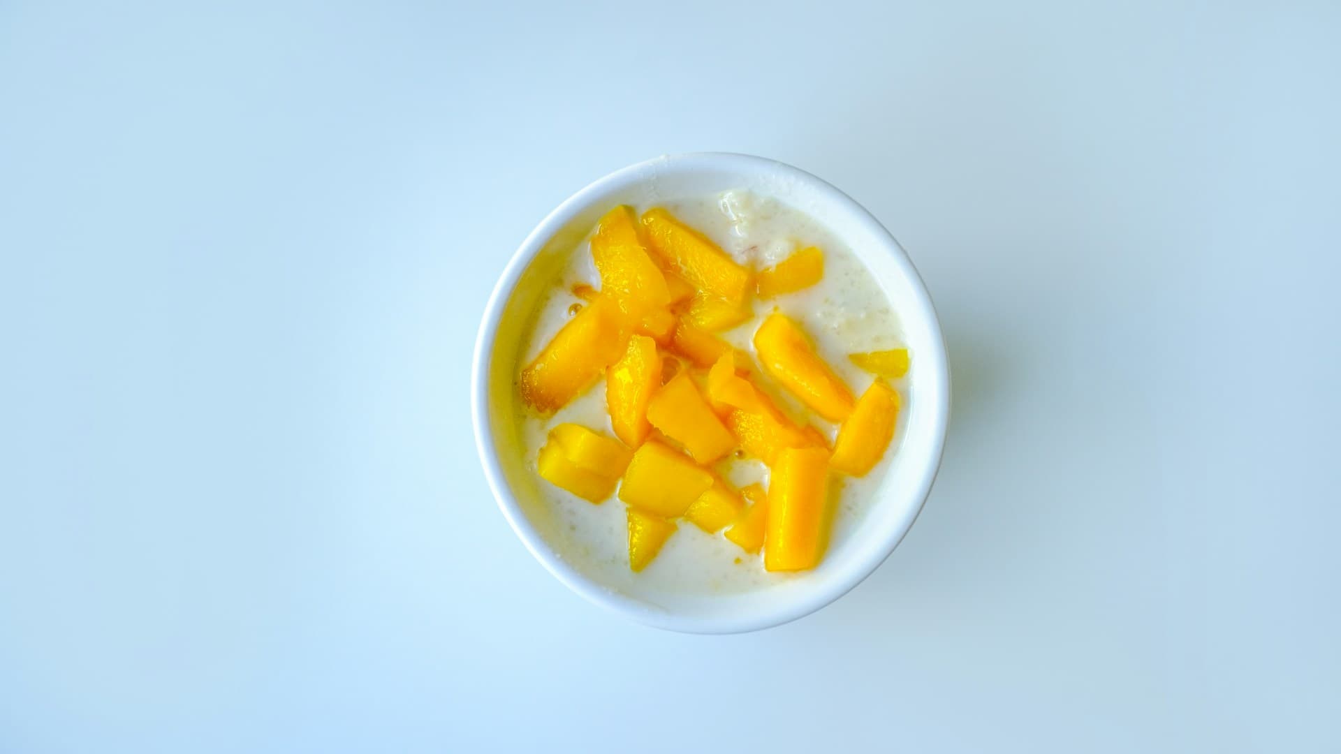 A close-up of beautifully grilled peaches served in a white bowl, topped with a dollop of Greek yogurt and a sprinkle of cinnamon.