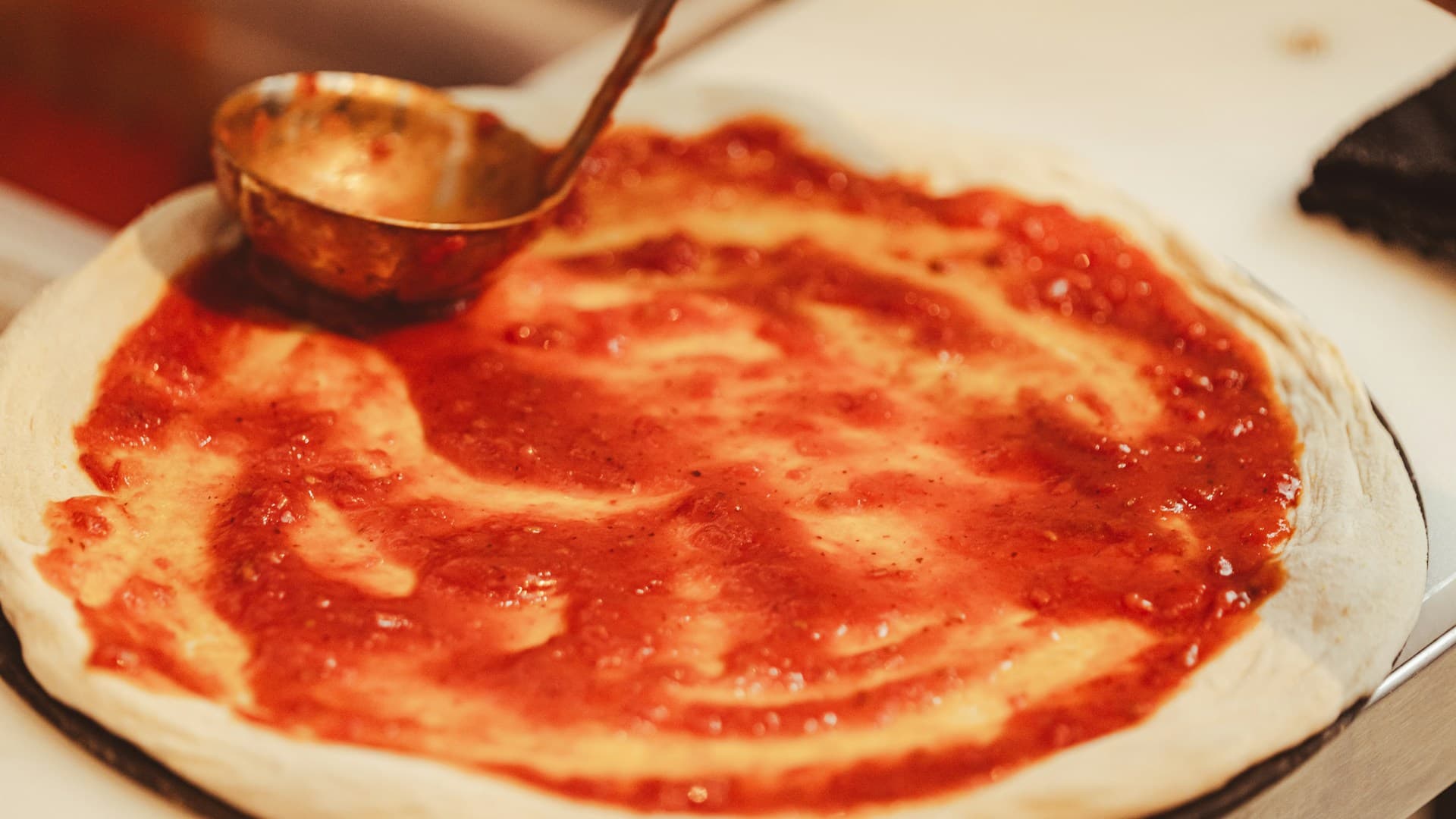 A close-up shot of a freshly baked carnivore pizza with a meat crust, topped with melted cheese and pepperoni, being sliced.