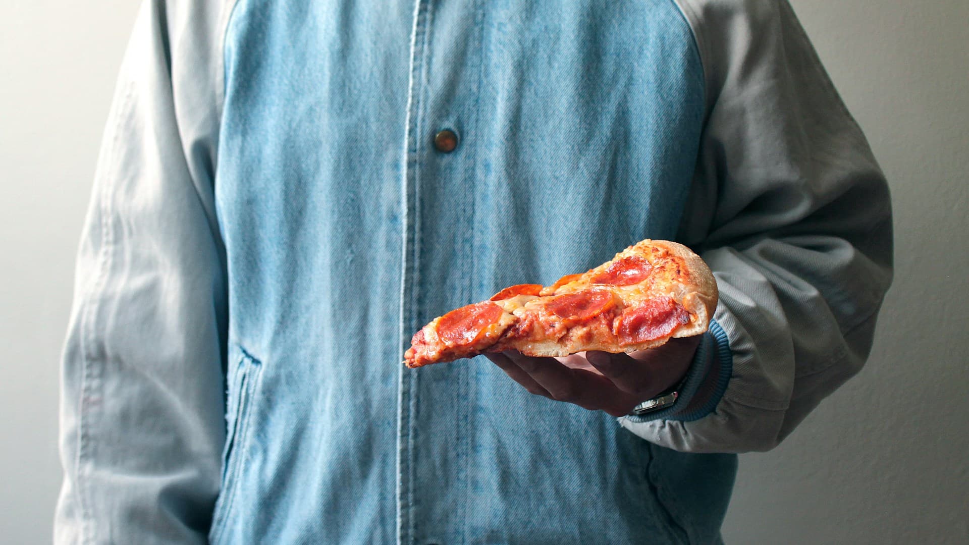 A concerned individual holding their stomach, with a background of carnivore diet foods like steak and eggs.