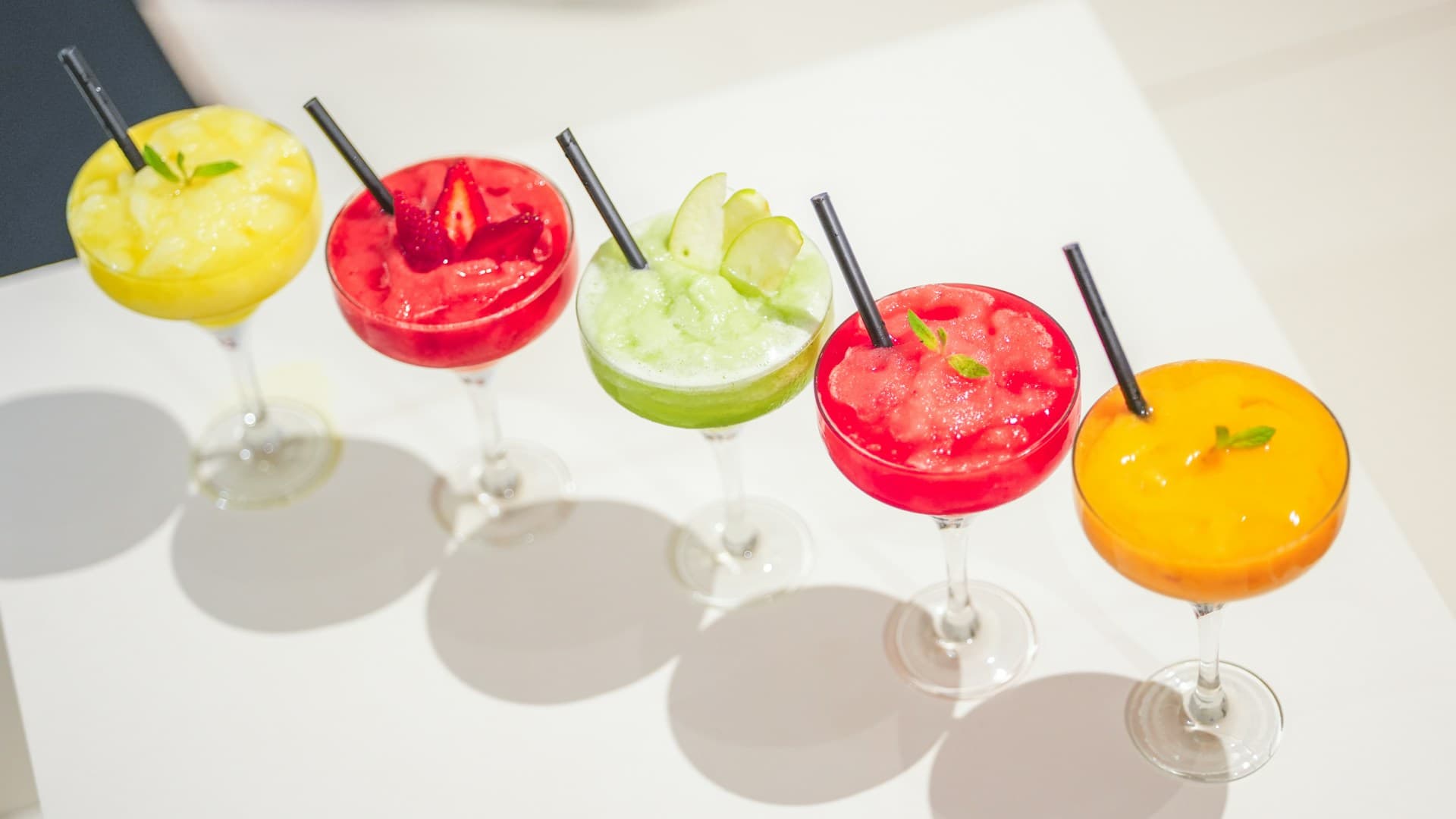 A lineup of five colourful Mediterranean smoothies in tall glasses, each showcasing different ingredients like berries, greens, and mango.