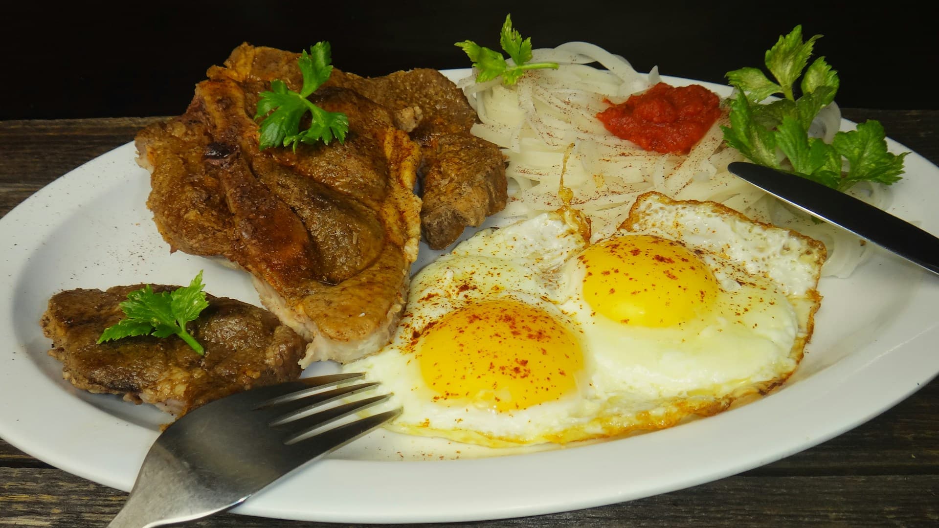 A perfectly cooked steak and sunny-side-up eggs on a plate, representing a classic carnivore diet breakfast.
