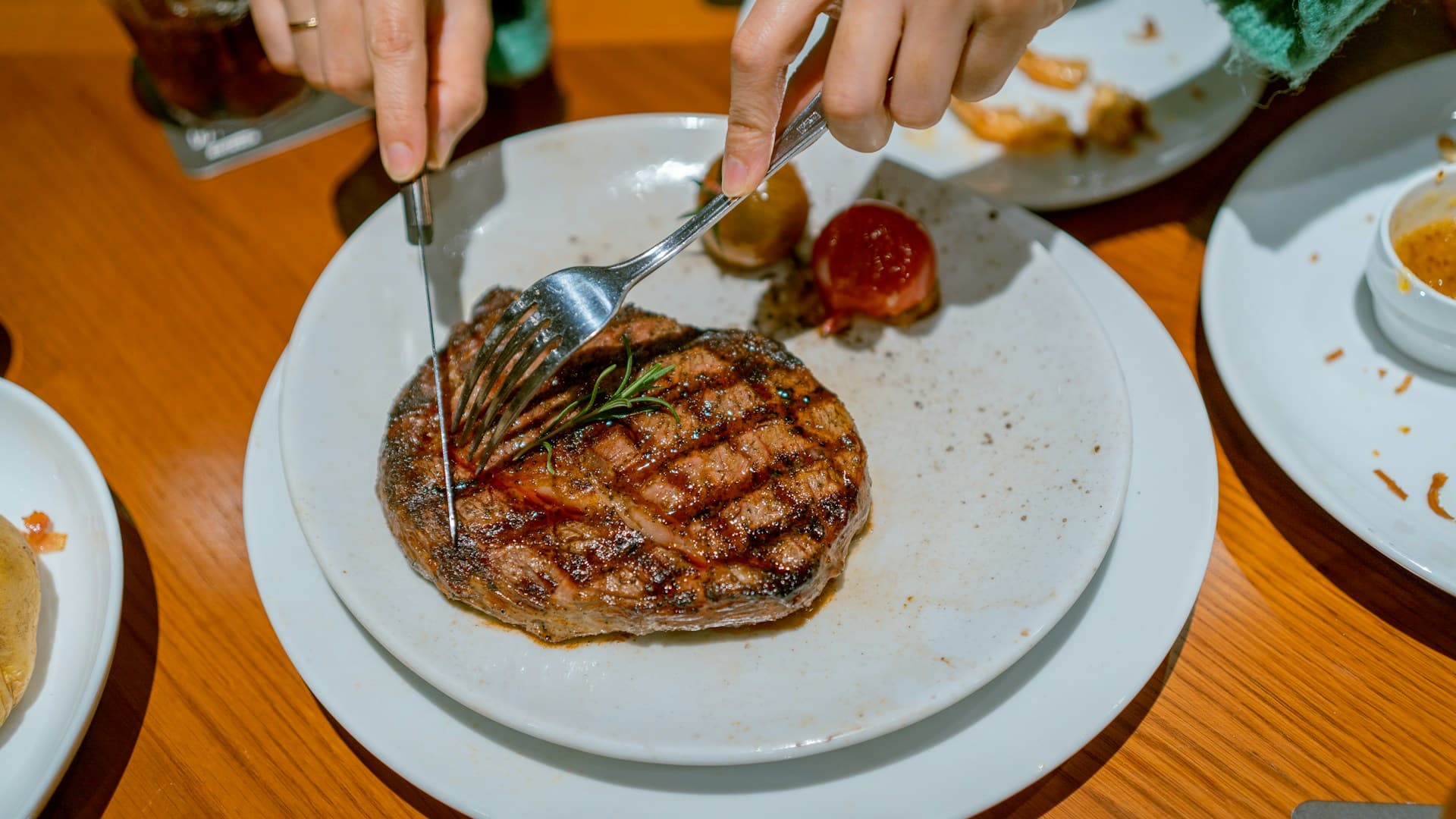 A person dining at a restaurant, looking at a simple plate of grilled steak, demonstrating how to navigate social situations on a carnivore diet.