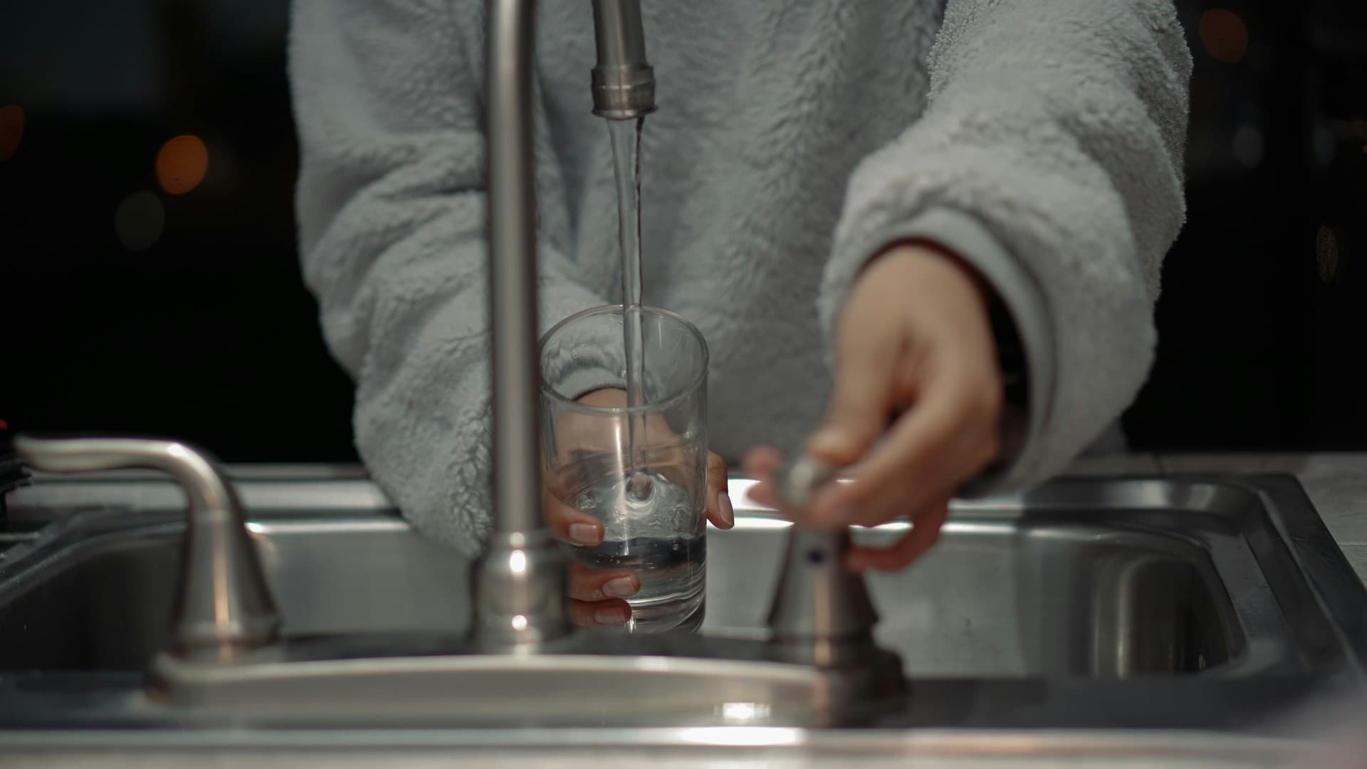 A person holding a glass of water with a salt shaker nearby, illustrating the importance of hydration and electrolytes.