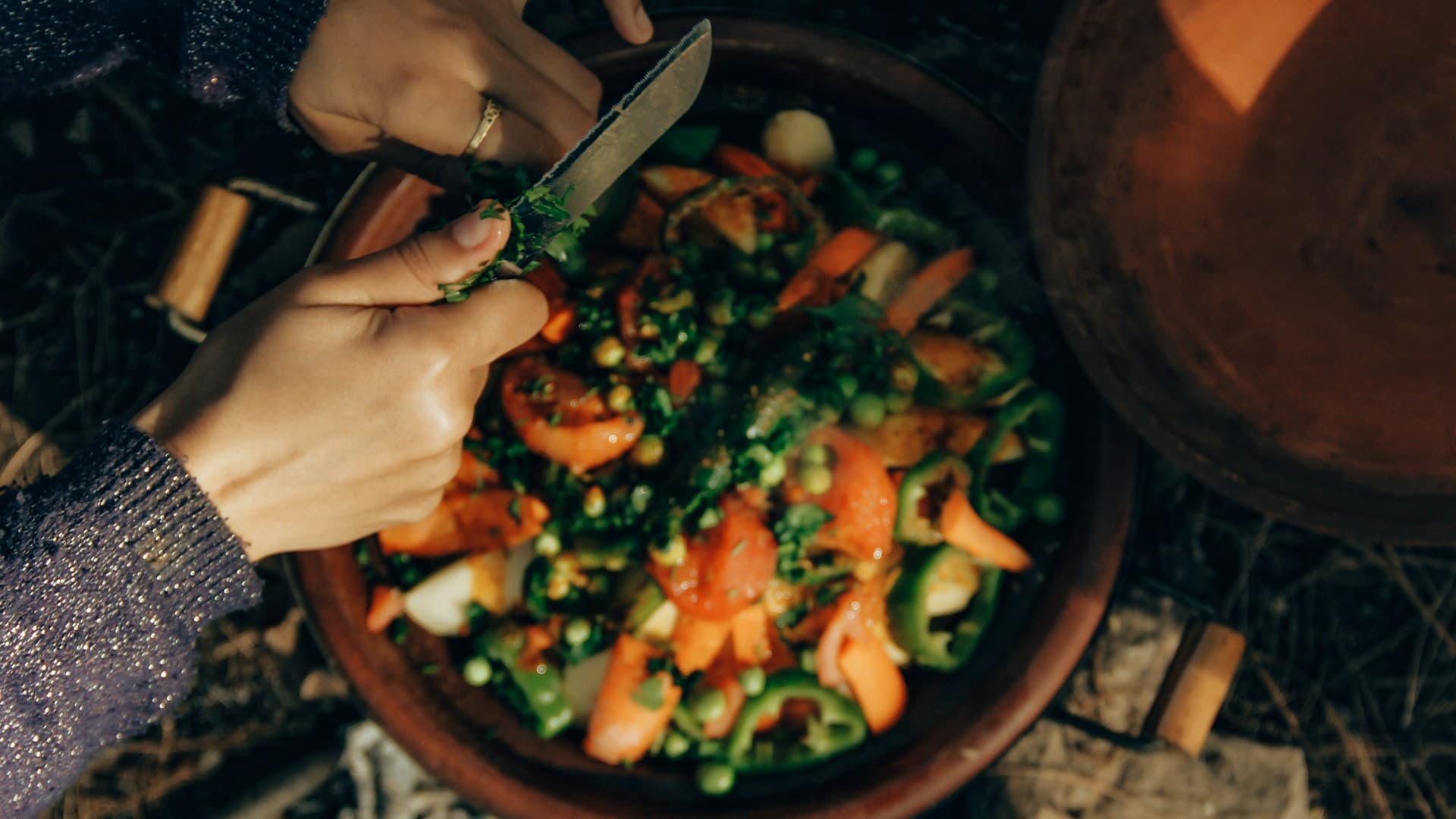 A person preparing a meal with fresh, budget-friendly Mediterranean ingredients like canned beans, frozen vegetables, and whole grains.