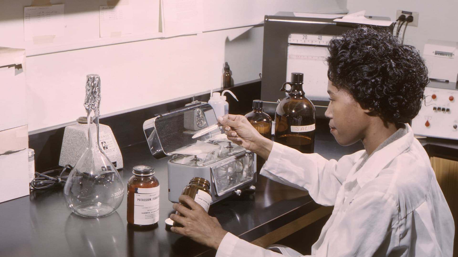 A scientist in a lab looking at a molecular model, representing the metabolic interaction of alcohol in the body.
