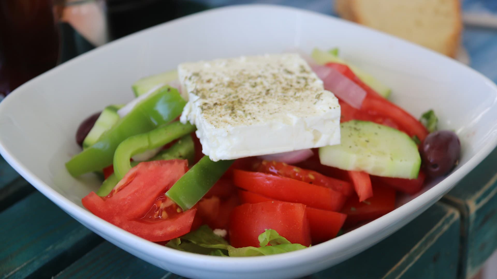A vibrant Mediterranean cucumber salad in a white bowl, garnished with fresh dill and feta cheese.