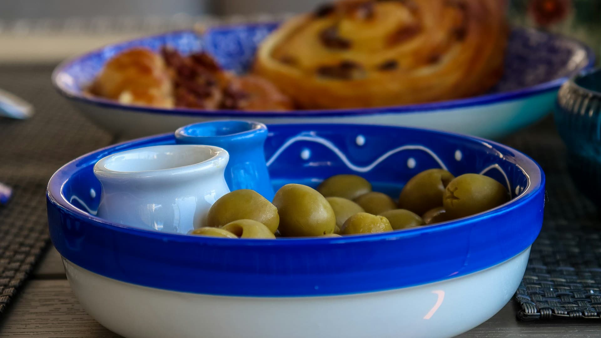 A woman in her kitchen assembling a healthy Mediterranean dessert with a bowl of Greek yogurt, fresh berries, nuts, and a drizzle of honey.