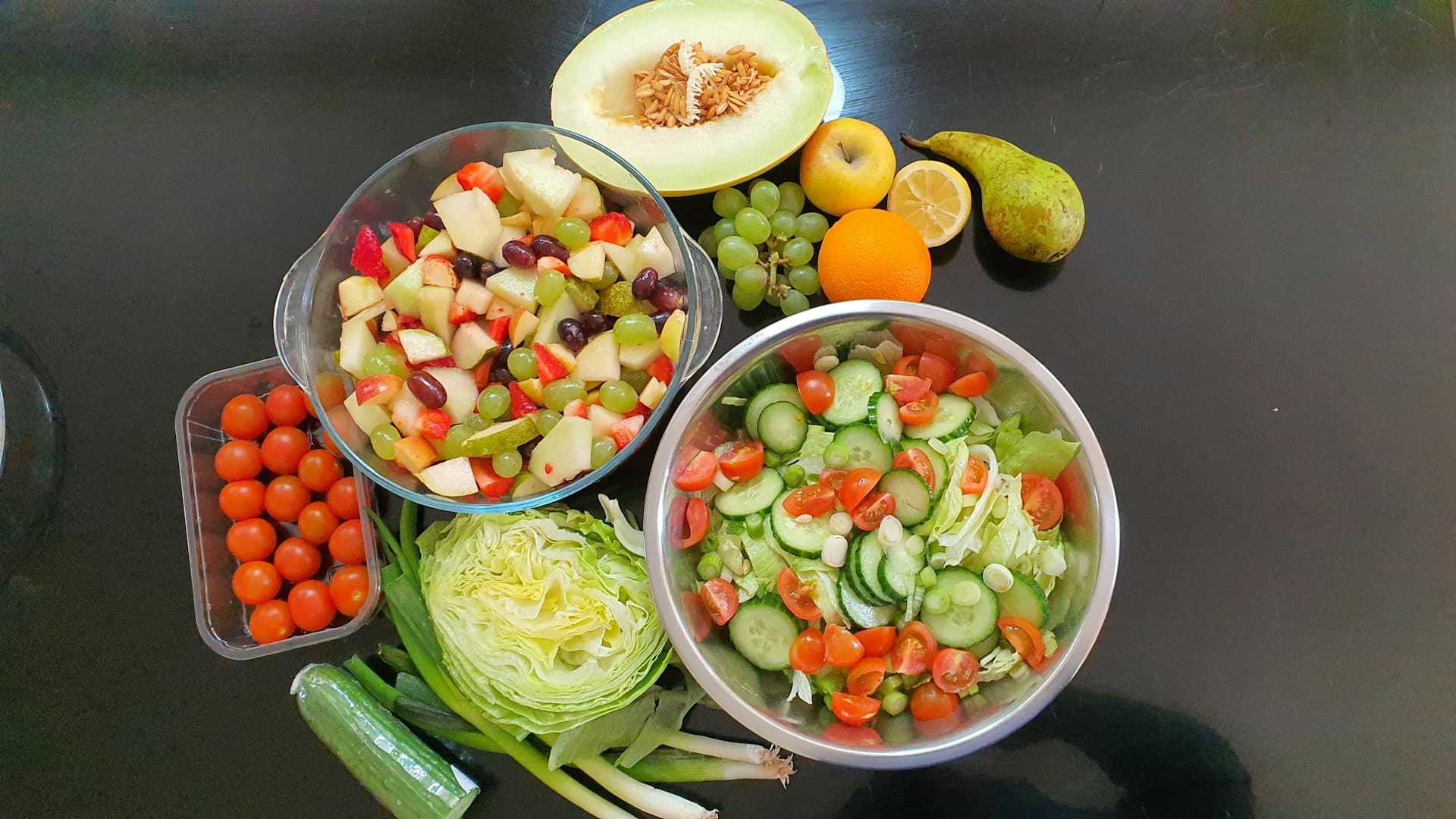 Meal prep containers showing separated cucumber salad components: chopped vegetables in one, and dressing in a small jar.